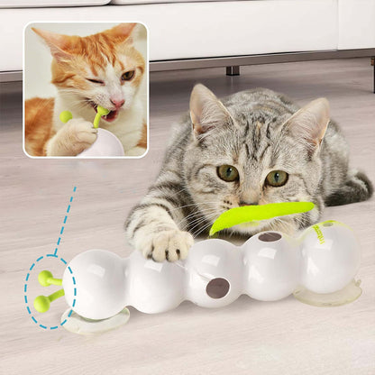 Cat playing with a white and green cat toy on a wooden floor.