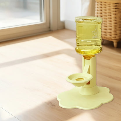 Yellow automatic water dispenser bottle holder with a flower-shaped base, shown on a wooden floor in a bright room. The image includes a product inset showing included accessories like a straws brush, suction cup, and transparent sticker.