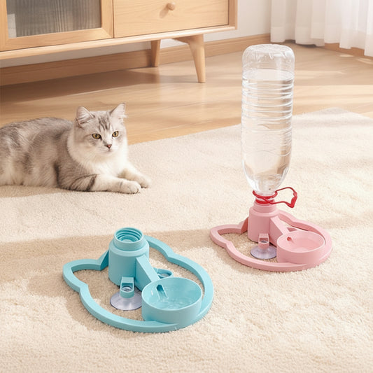 A pet water fountain shown on a beige carpet in a home setting, with a cat blurred in the background. The fountain has two color options: a light blue version with a suction cup base and a clear plastic bottle, and a pink version with a suction cup base and a clear bottle.