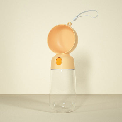 Portable pet water bottle with orange top and clear base on a beige background